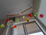 Colorful red, brown, green and clear glass balls hanging from a string on a ceiling