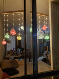 Decorative string lights on a glass door with reflections of indoor furniture.