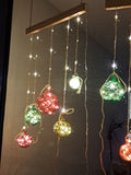 Decorative string lights with colorful bulbs on a reflective surface in the dark