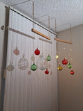 Decorative christmas red, green and clear blown glass orbs with fairy lights, stronger light shadows the orb lights; reflecting on a white wall with a textured ceiling.