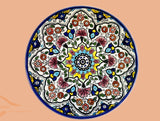 Red yellow dark blue & light blue colorful teleidoscope patterns on glazed earthenware ceramic flat plates. Own&Adore Mystic Land Painted Creations. Eid Decorations. Palestinian pottery art and ceramic