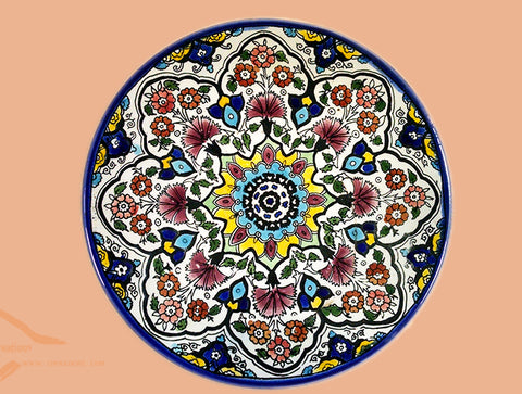 Red yellow dark blue & light blue colorful teleidoscope patterns on glazed earthenware ceramic flat plates. Own&Adore Mystic Land Painted Creations. Eid Decorations. Palestinian pottery art and ceramic